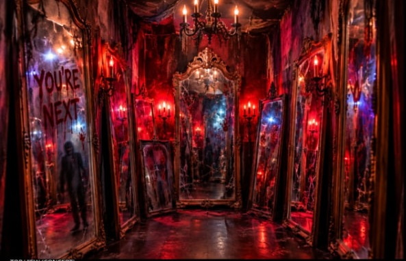 Red-lit mirror room with aged mirrors and a candle chandelier